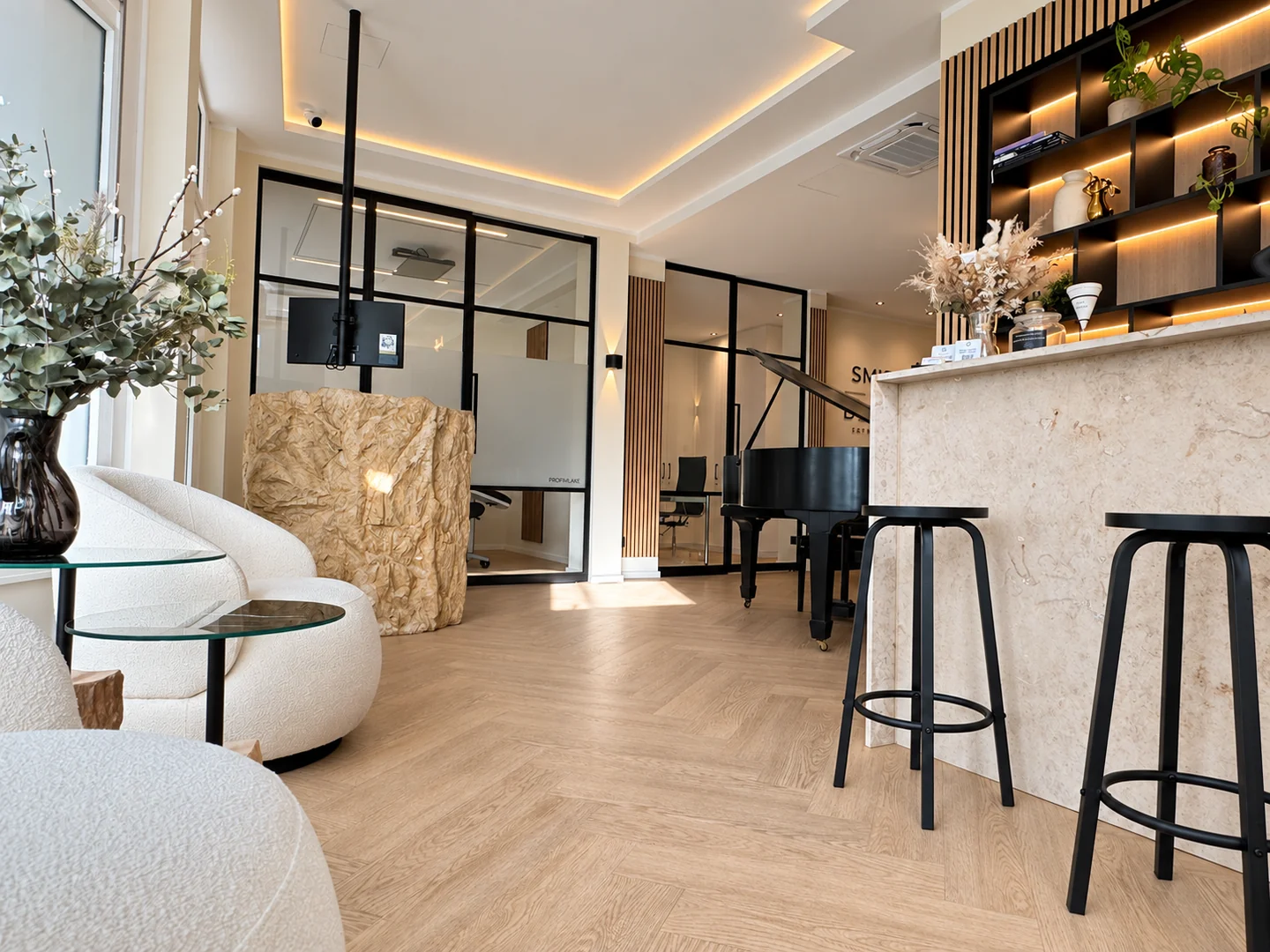 Empfangsbereich von Smile Meets Design in Köln mit hellen Sesseln, Flügel und Natursteintresen